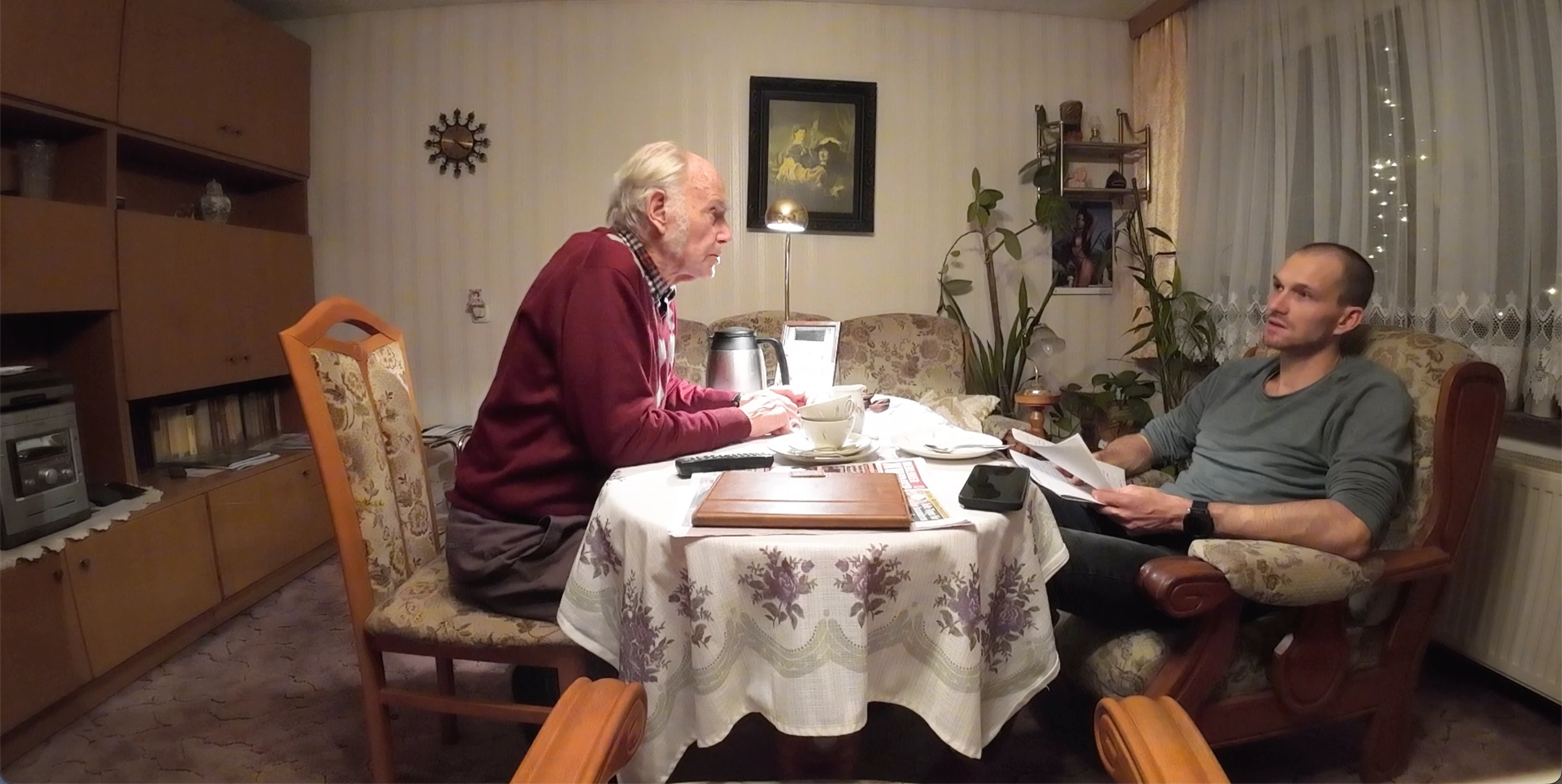 Michael hört seinem Opa beim Interview am Wohnzimmertisch zu.